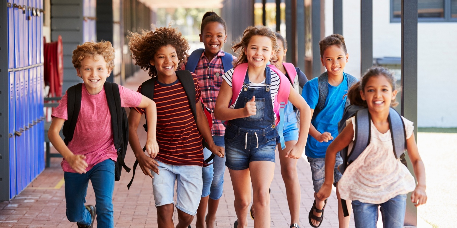 Group of smiling kids running down school hallway