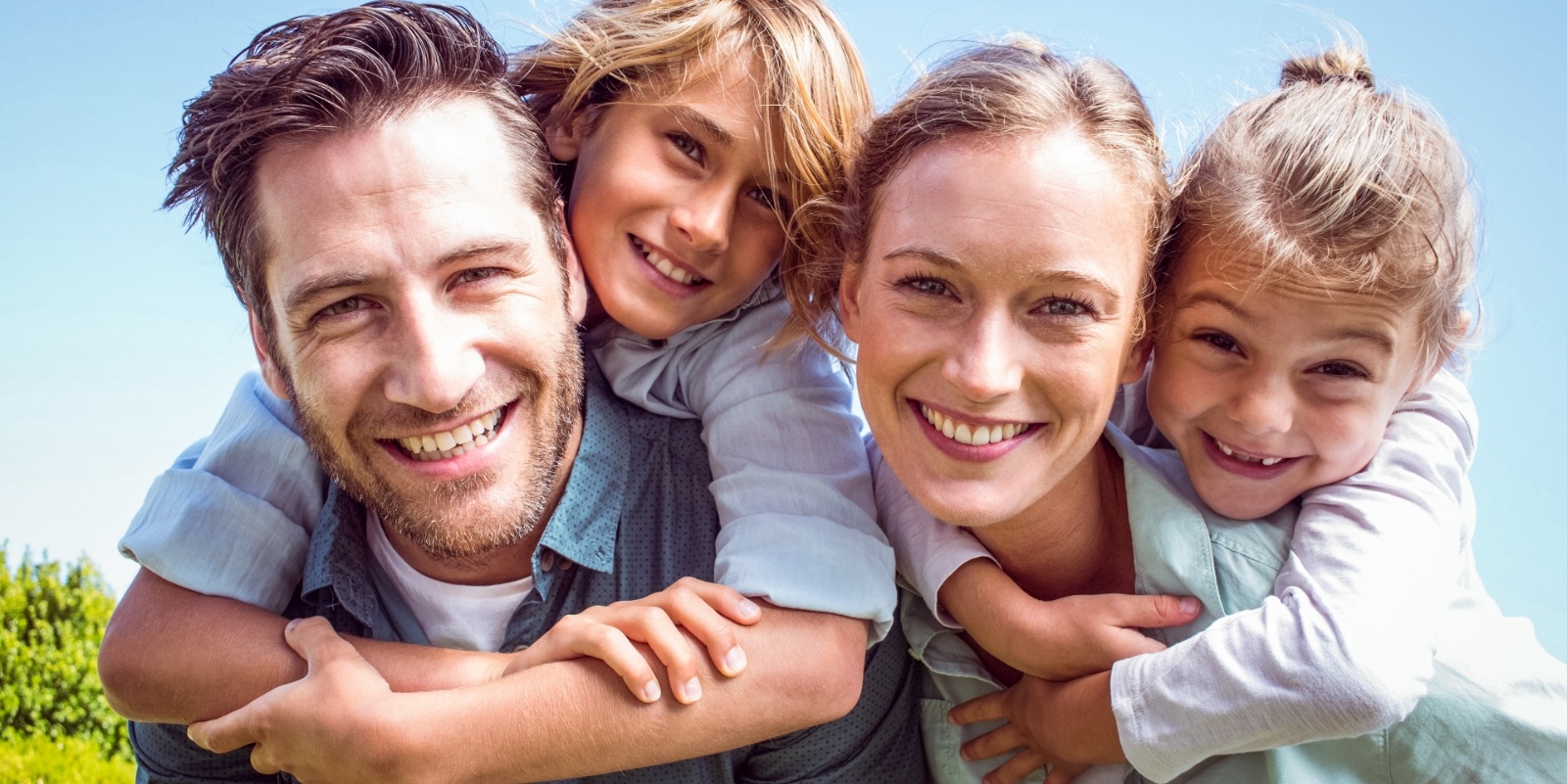 Smiling family of four hugging outdoors