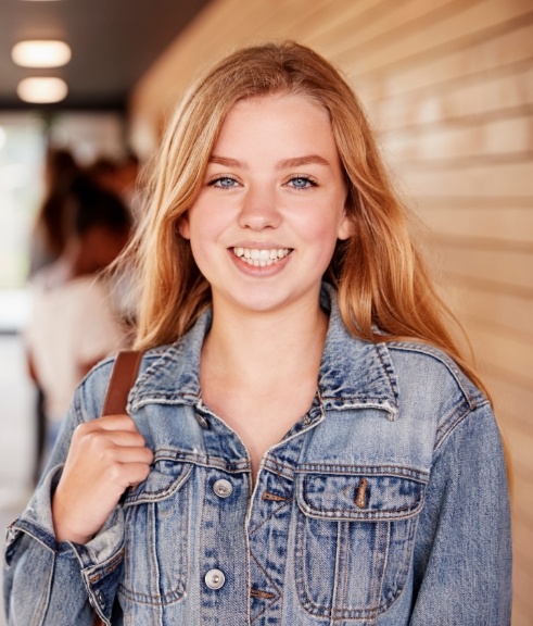 Teenage girl with backpack smiling in school hallway