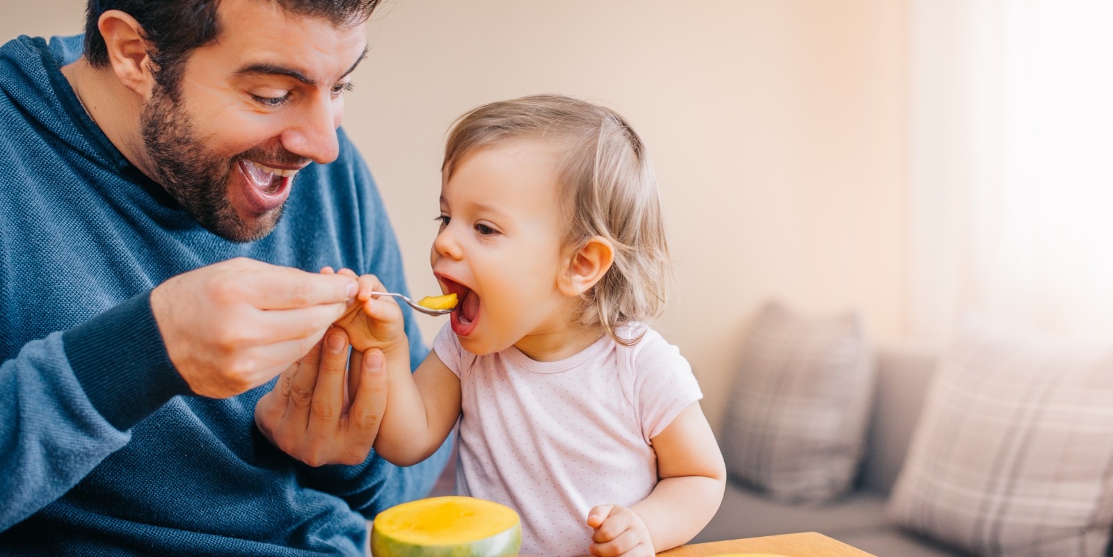 Father feeding his child fruit after tongue tie treatment in Hamilton